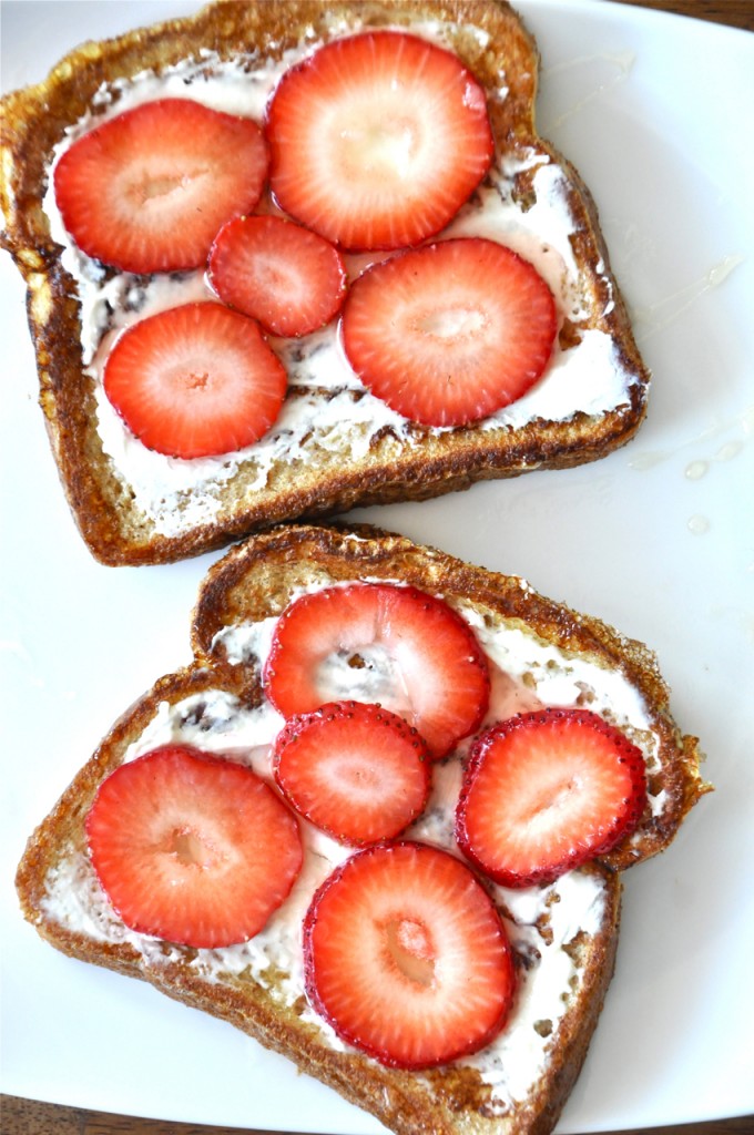 Plate with slices of toast topped with cream cheese and strawberries