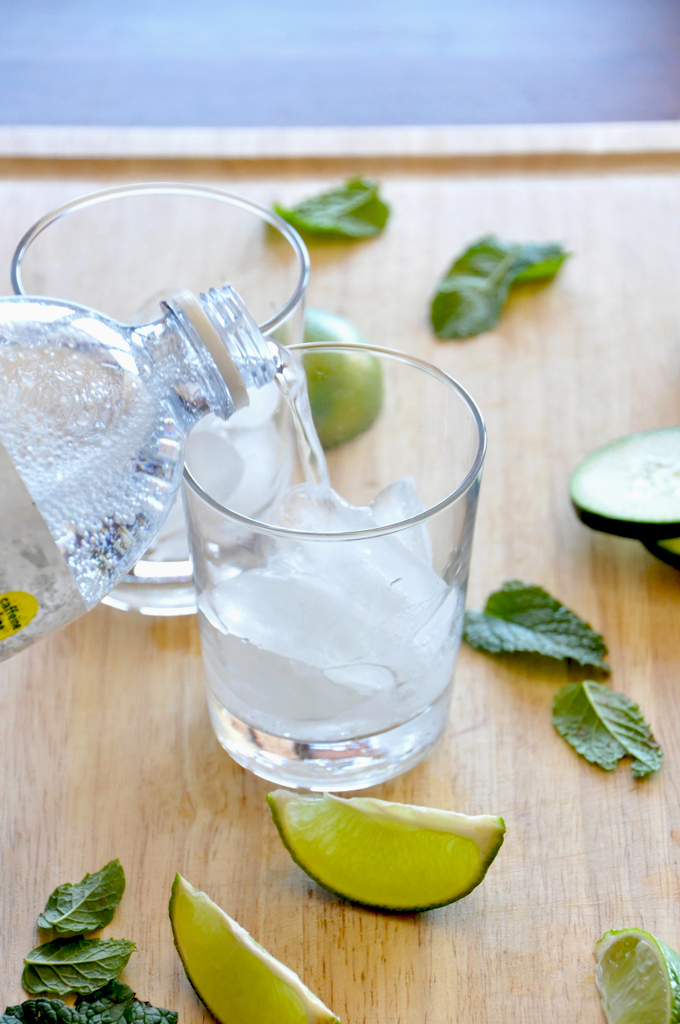 Pouring tonic water into glasses to make our Cucumber Cooler Cocktails recipe