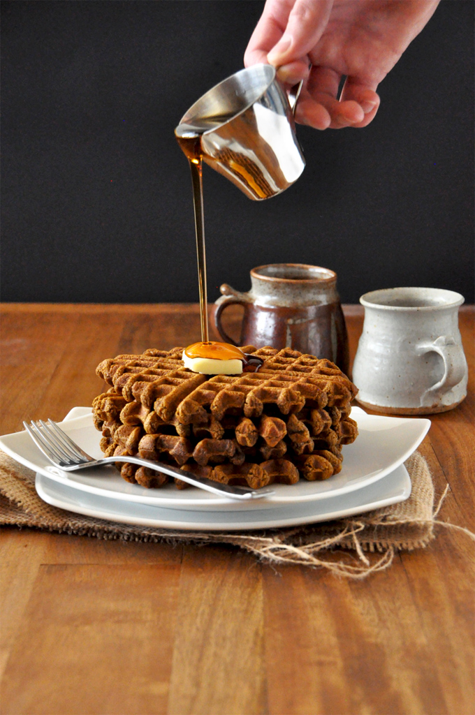 Pouring syrup onto a stack of Vegan Gingerbread Waffles