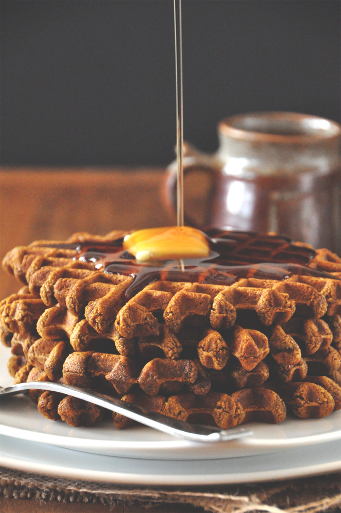 Drizzling syrup onto a slab of vegan butter perched on top of delicious homemade Gingerbread Waffles