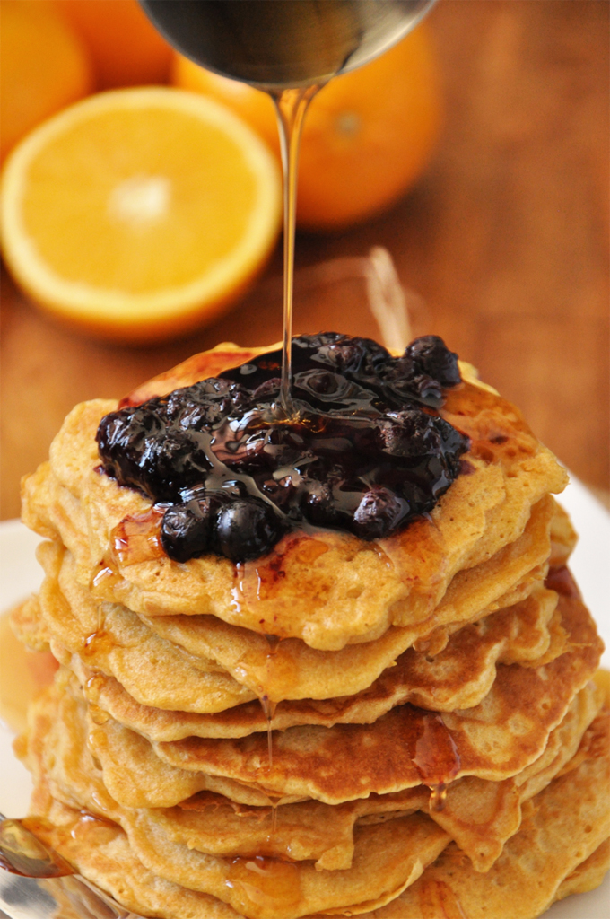 Close up shot of drizzling syrup onto griddle cakes for a delicious breakfast