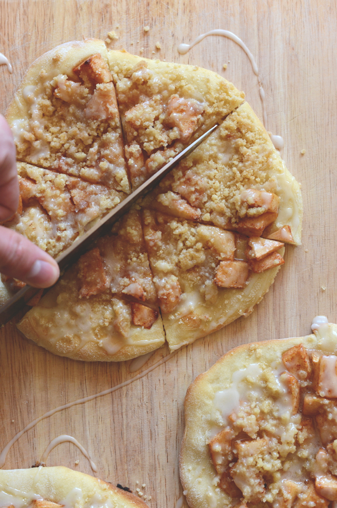Using a large knife to cut an Apple Streusel Breakfast Pizza into bite-sized pieces