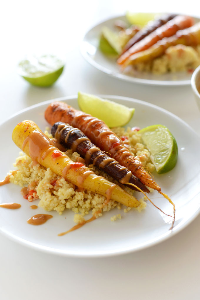 Plate of millet and Curry Roasted Carrots drizzled with peanut sauce and sriracha