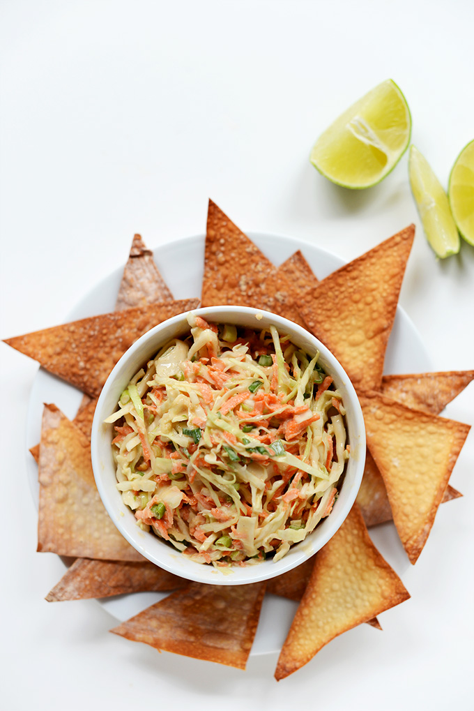 Bowl of Creamy Thai Slaw surrounded by Baked Wonton Chips and limes