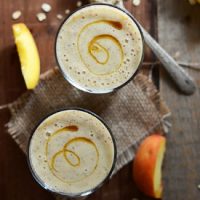 Top down shot of two glasses filled with our Peach Oat Smoothie recipe