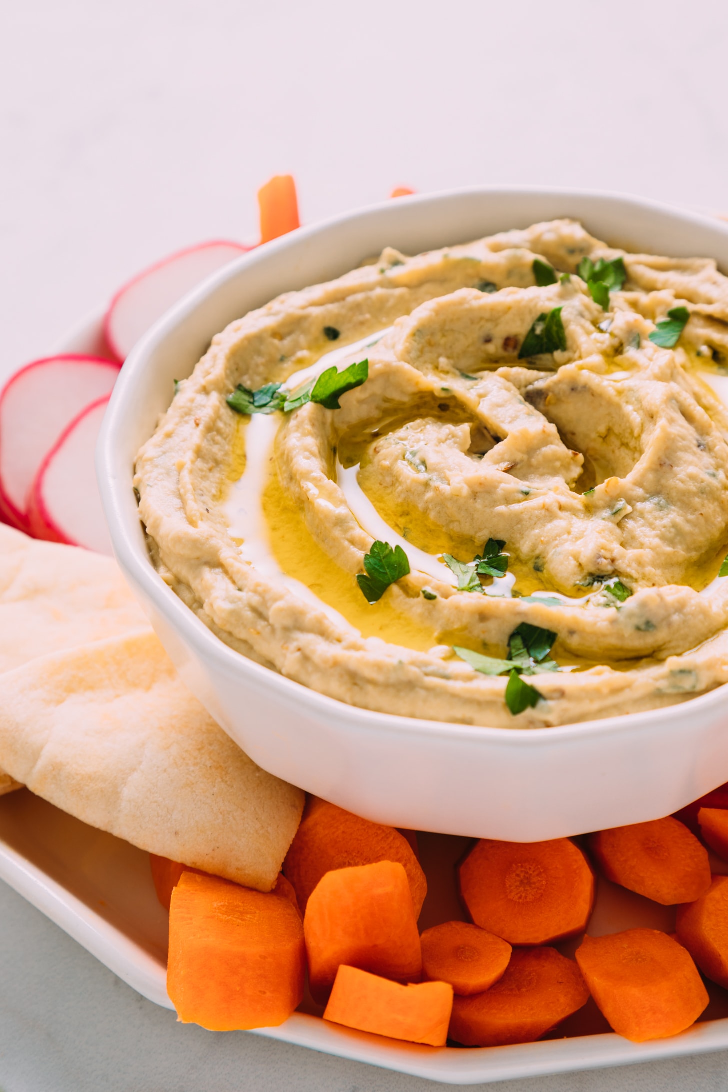 Veggies and pita bread surrounding a bowl of our baba ganoush recipe