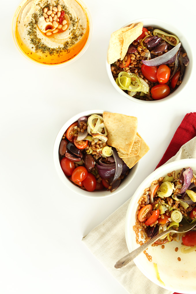 Bowls of Mediterranean Wheat Berry Salad with pita chips and hummus