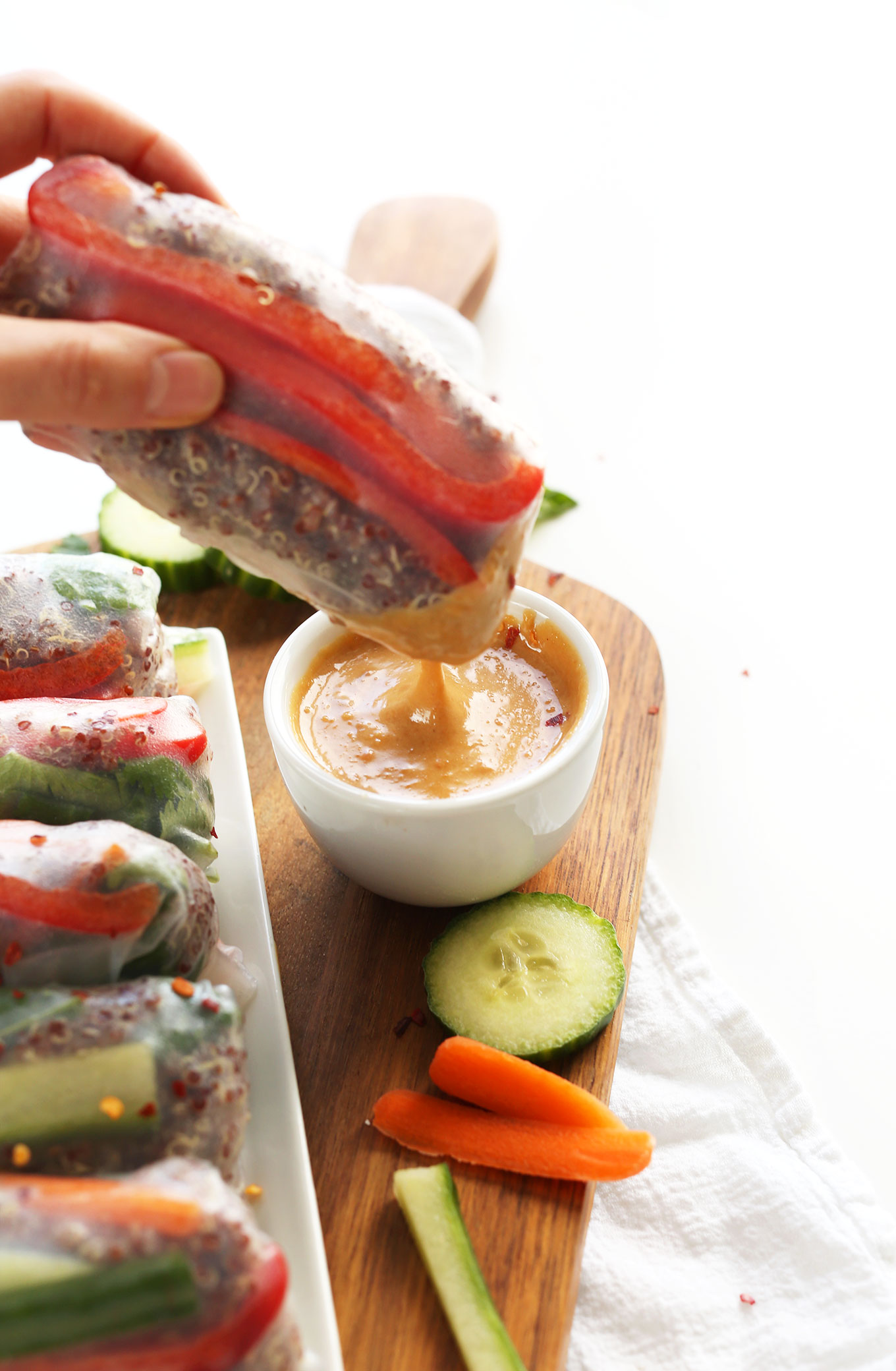 Dipping a Quinoa Spring Roll into a bowl of Cashew Dipping Sauce