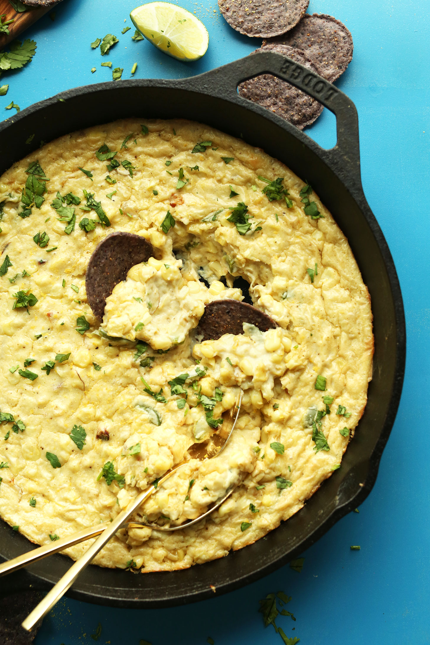Dipping blue corn chips into Cheesy Vegan Corn Dip with Jalapenos