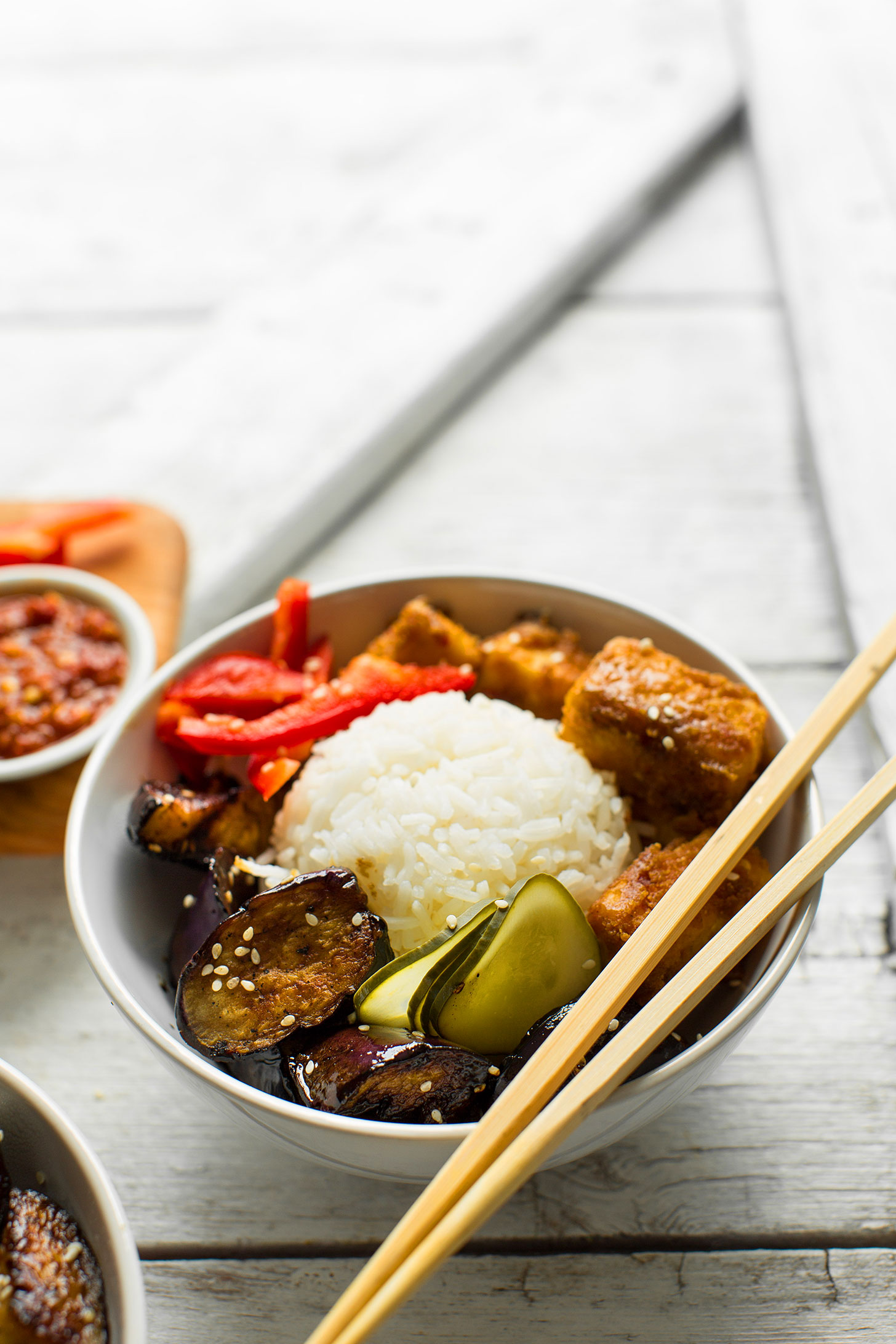 Bowl of Sesame Eggplant & Almond Butter Tofu with rice and chopsticks