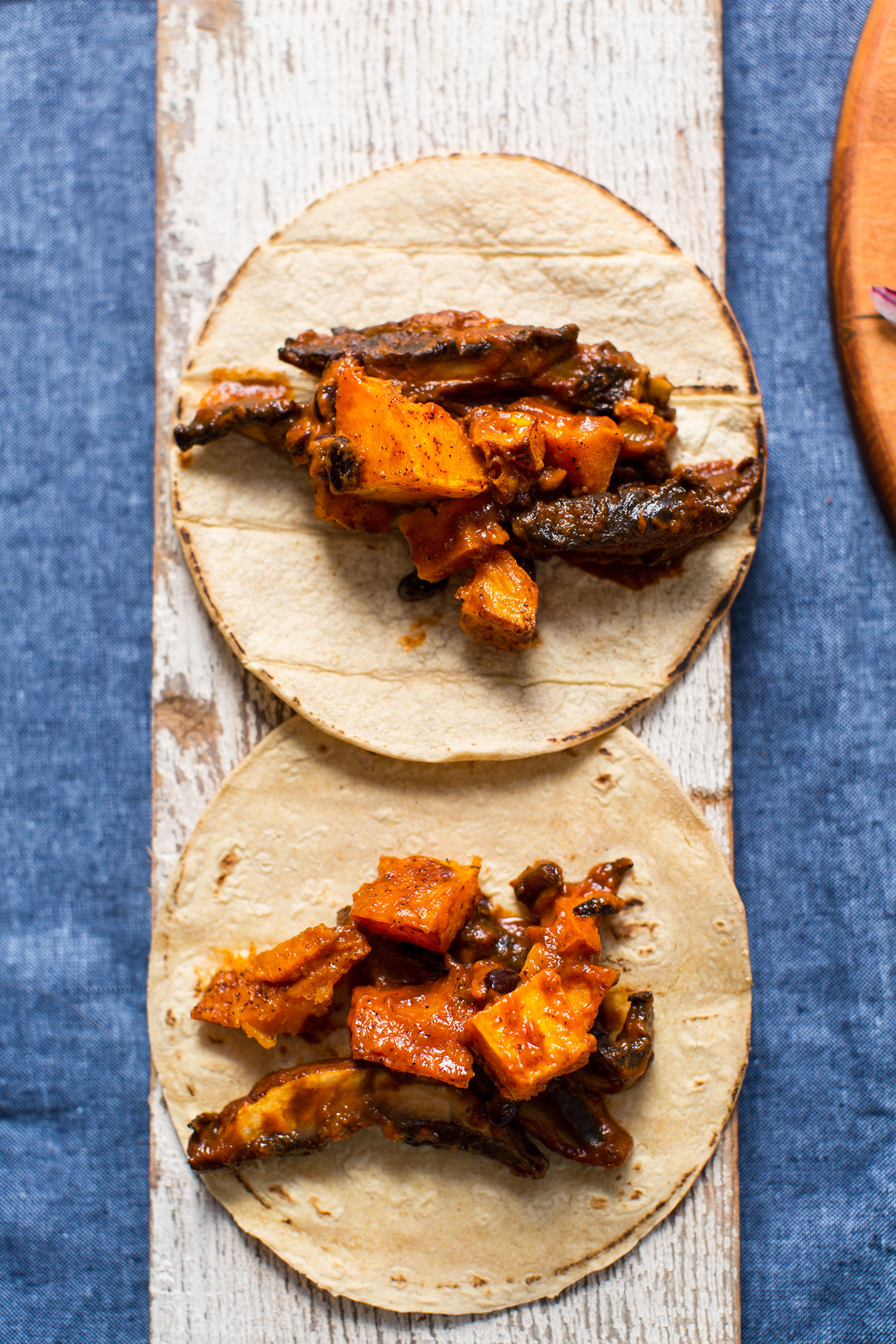 Wood plank displaying saucy gluten-free vegan Butternut Squash Tacos