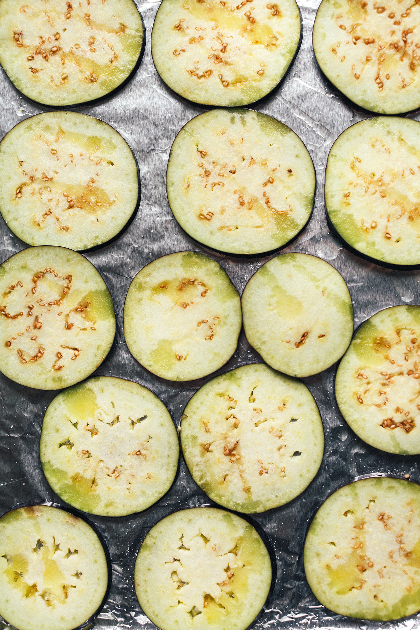 Thinly sliced eggplant drizzle with olive oil on a baking sheet 