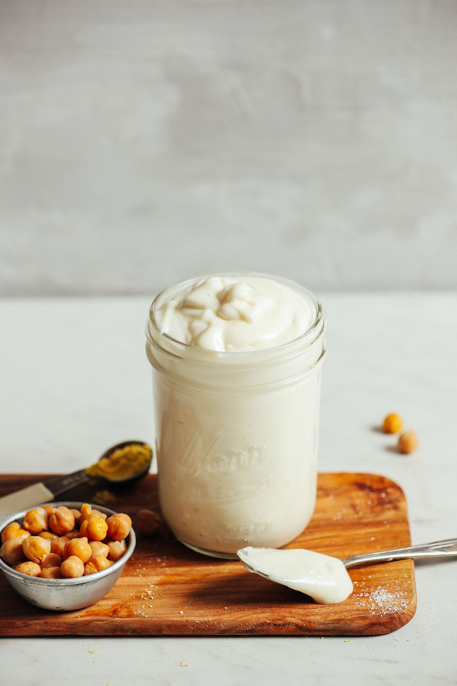 Jar filled with a batch of our vegan mayo recipe alongside ingredients used to make it