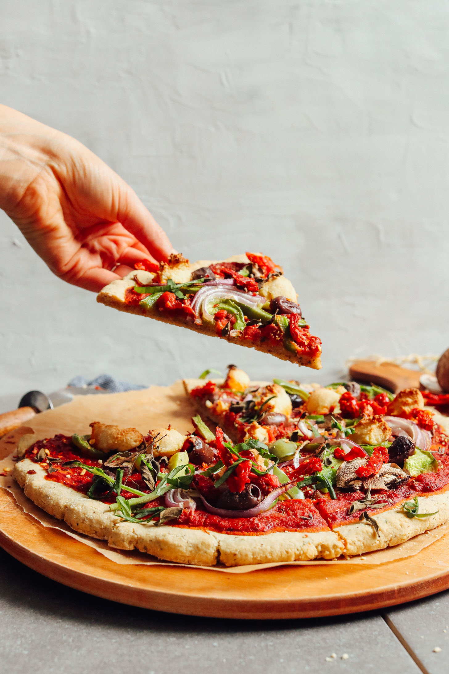 Picking up a slice of gluten-free and vegan pizza made using our Gluten-Free Pizza Crust recipe