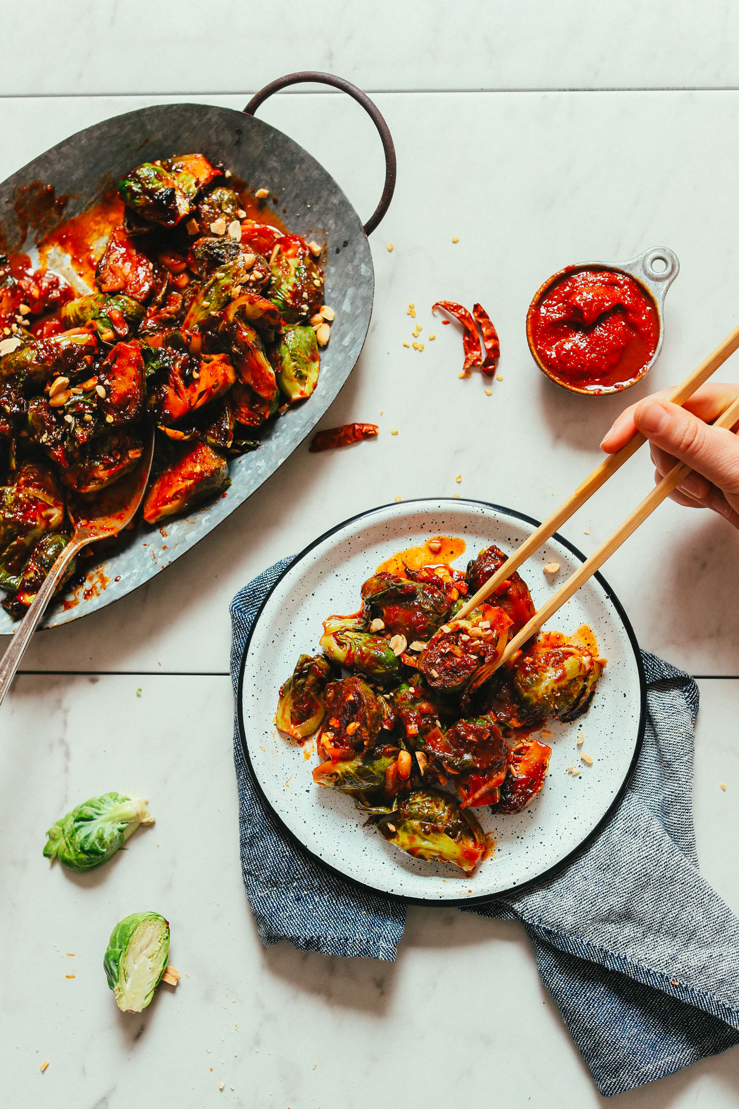 Using chopsticks to grab a bite of our Gochujang Stir-Fried Brussels Sprouts recipe