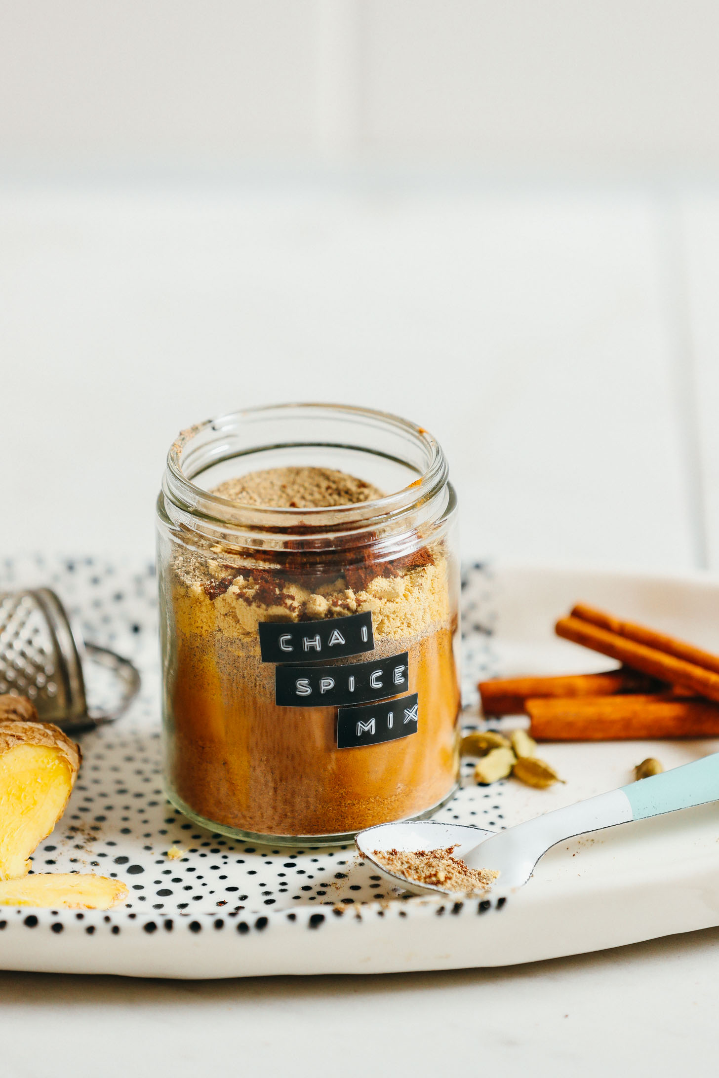 Jar of homemade caffeine free chai mix on a platter with ingredients used to make it