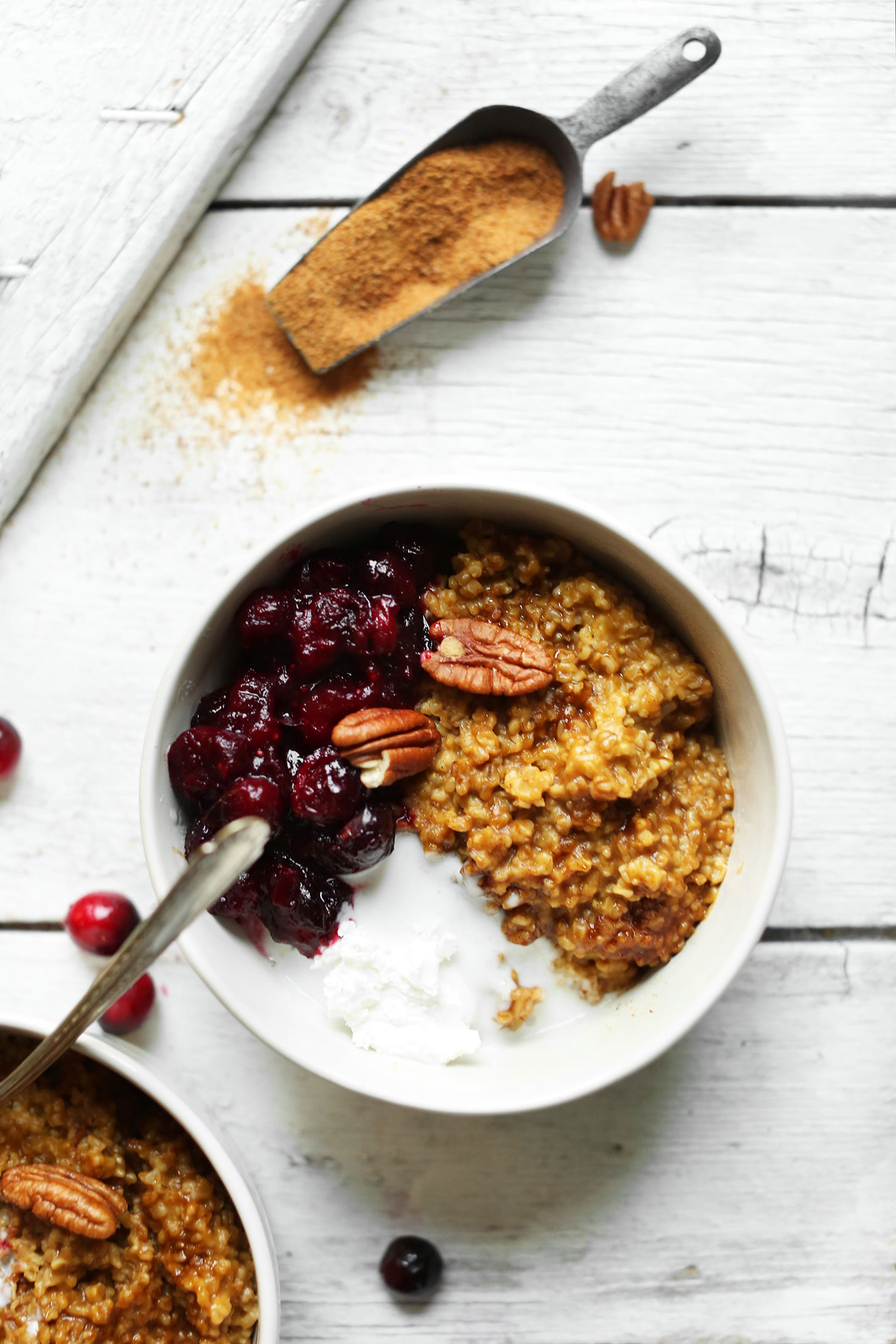 Bowl of steel cut oats made with pumpkin and topped with cranberry compote and coconut whipped cream