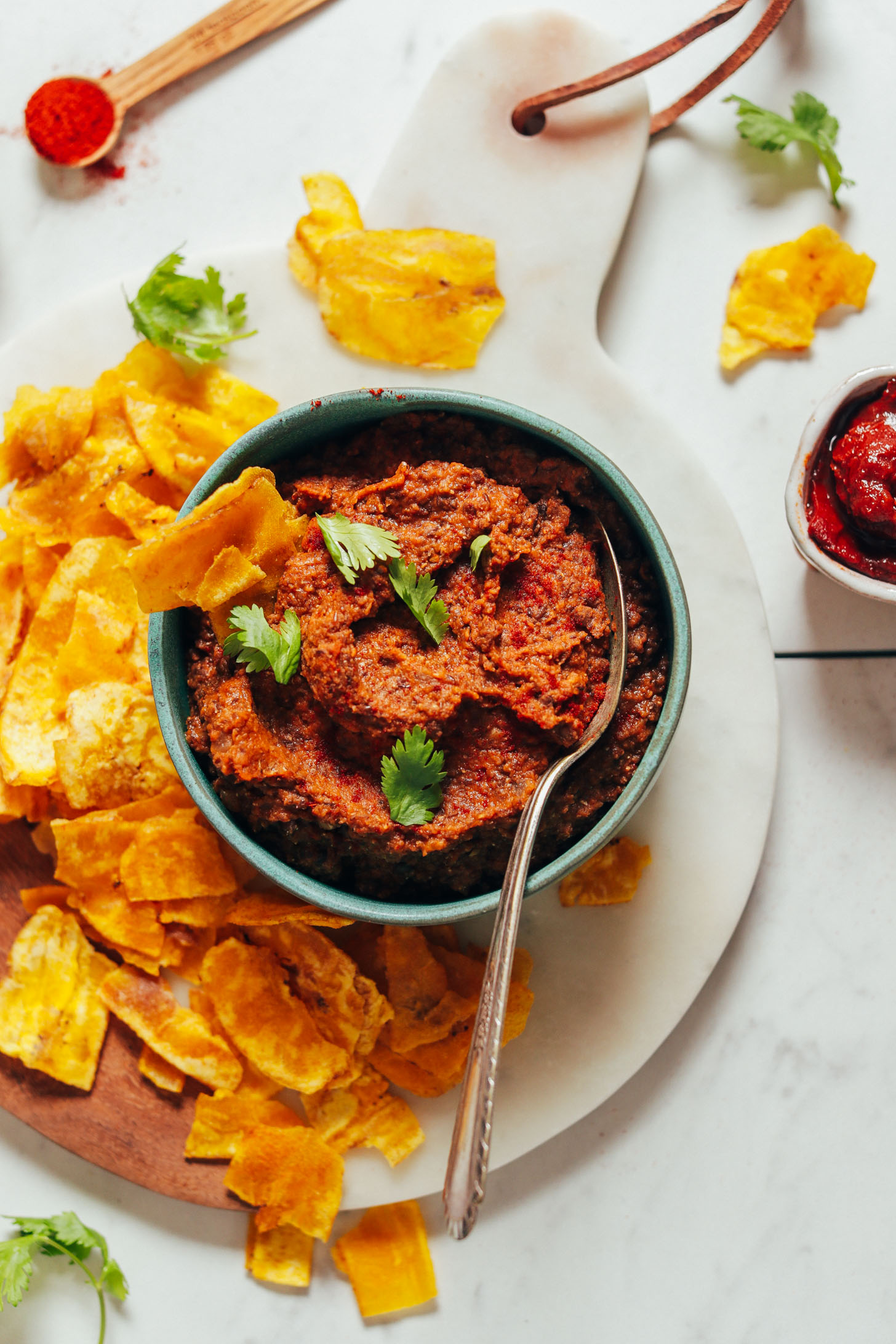 Plantain chips beside a bowl of Smoky Refried Lentils