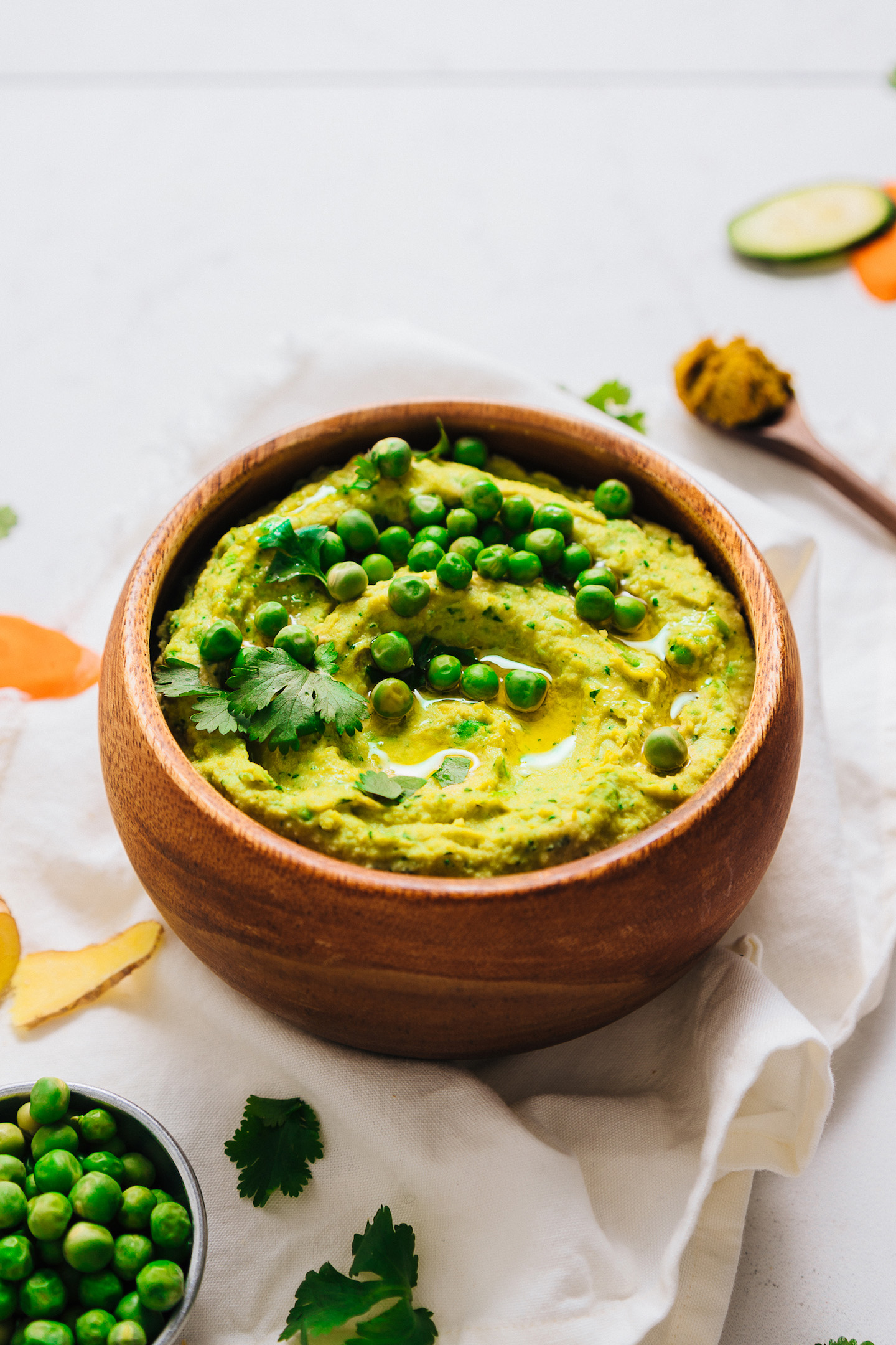 Bowl of Green Pea Curry Hummus topped with fresh cilantro and peas