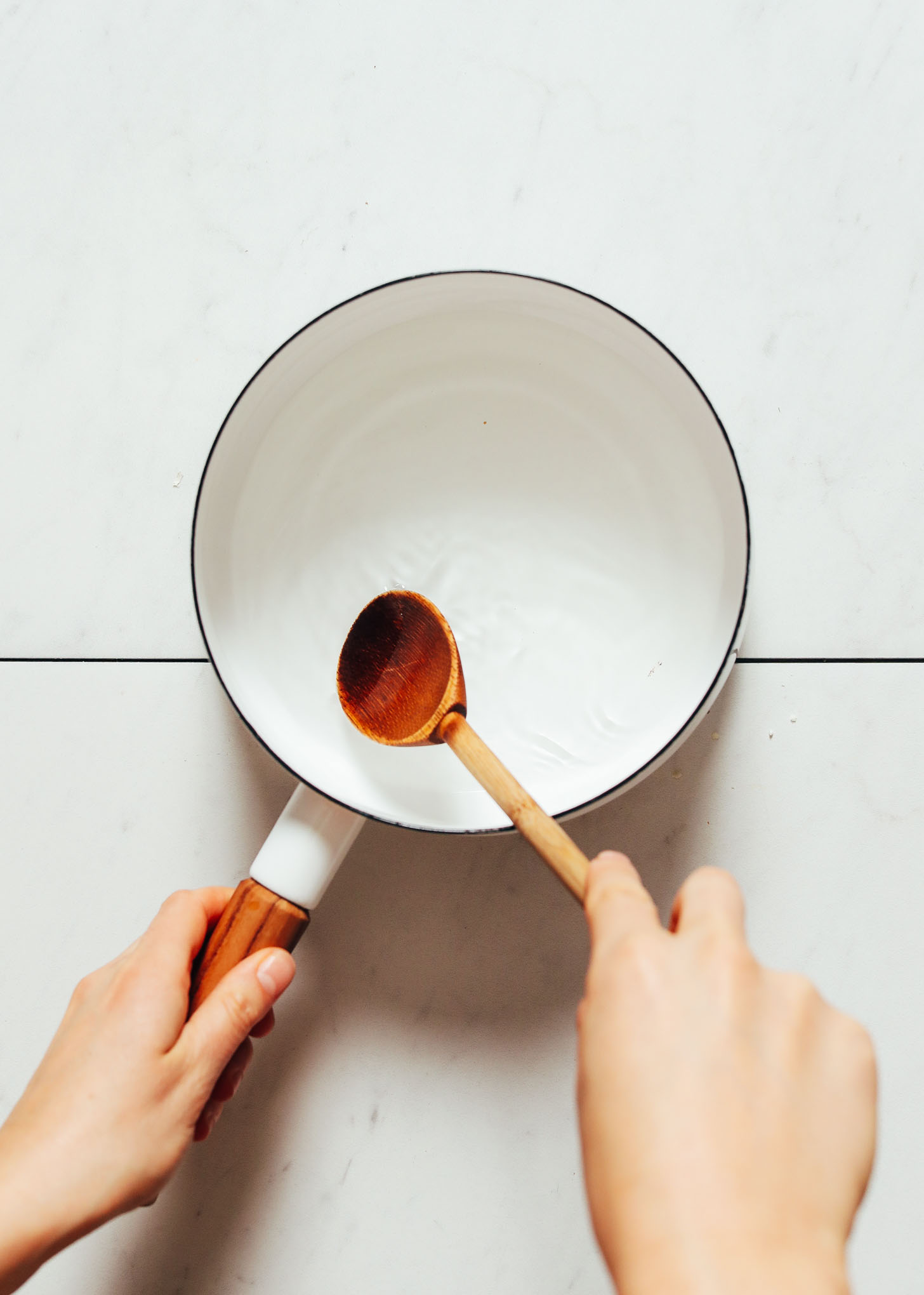 Using a wooden spoon to stir a pot of heated vinegar for making Escabeche