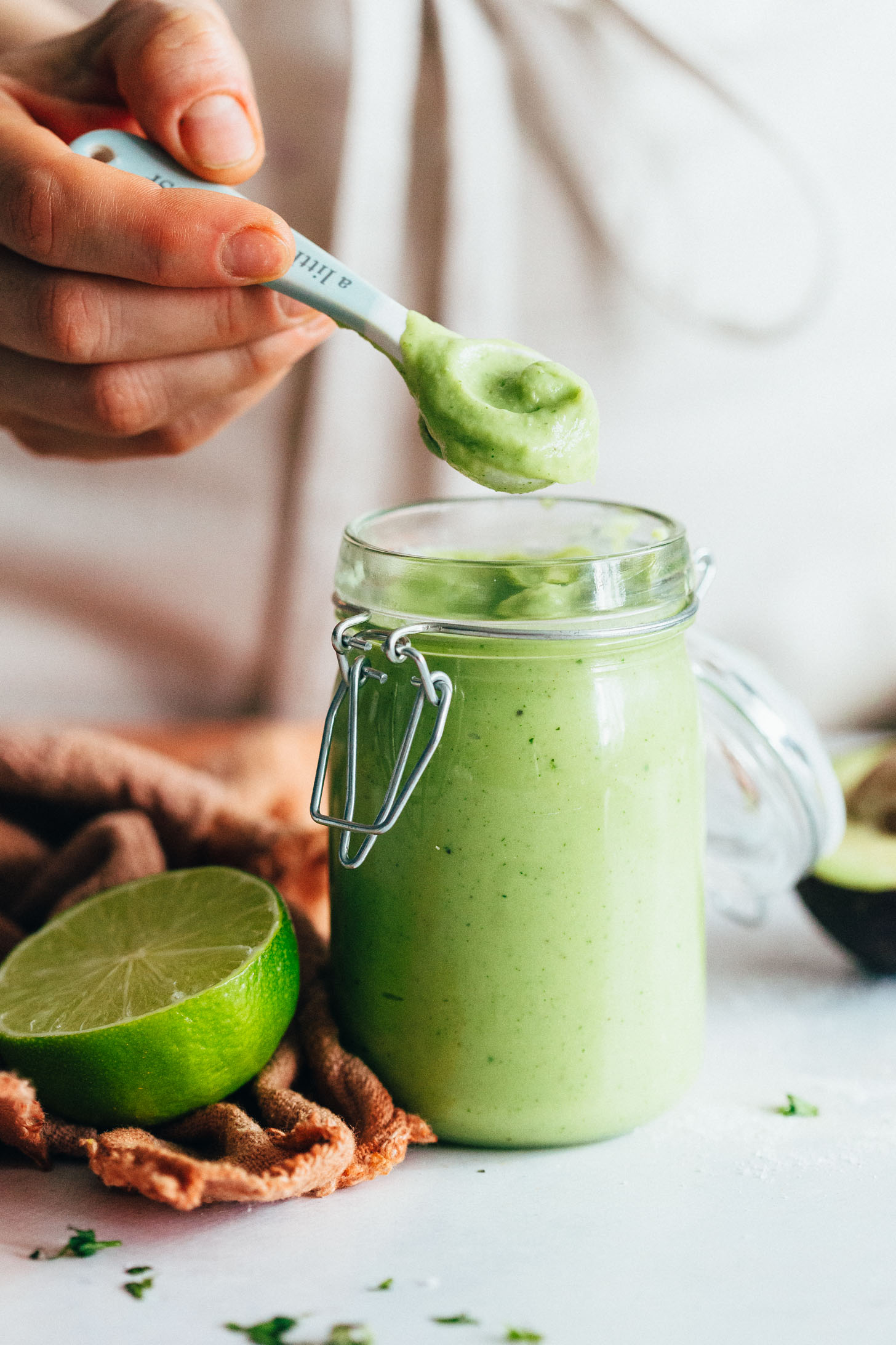 Holding a spoonful of creamy vegan aioli over a jar