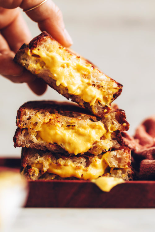 Picking up a vegan grilled cheese sandwich from a stack