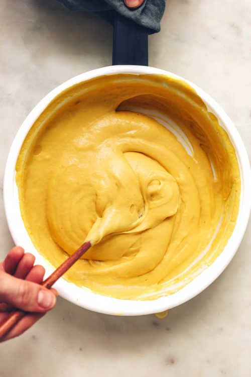 Stirring a pan of vegan cheddar cheese