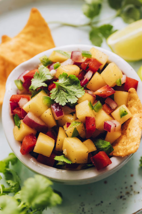 Tortilla chips in a bowl of fresh mango salsa