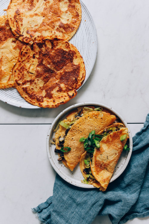 Plate of chickpea pancakes and another plate with them filled with a leek mushroom filling