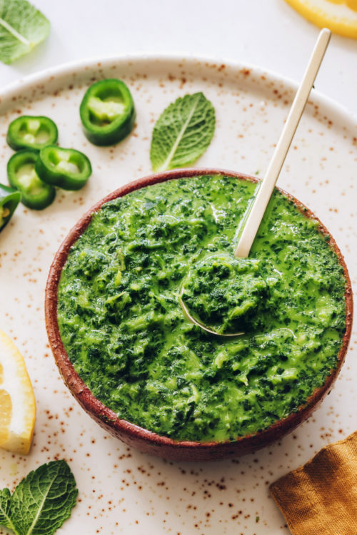 Mint leaves and cilantro surrounding a bowl of our mint chutney recipe