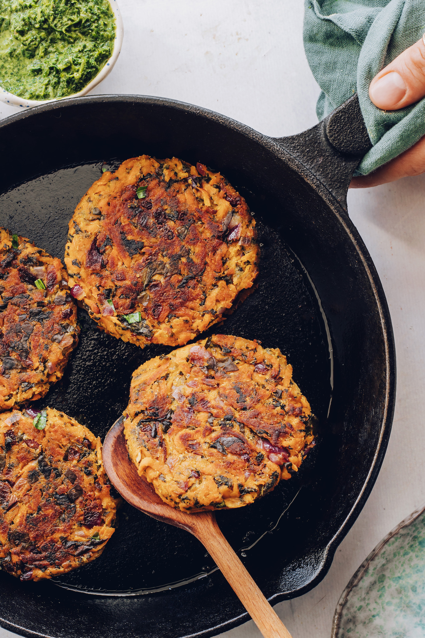 Bowl of mint chutney next to a pan of sweet potato fritters