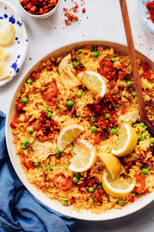 Pan of vegan paella topped with lemon wedges