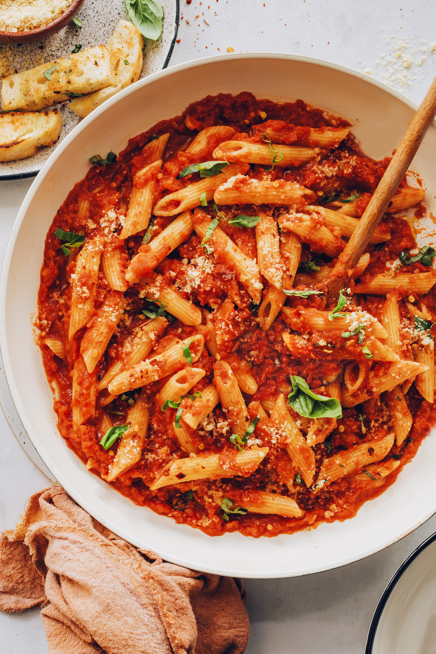 Slices of garlic bread next to a pan of our easy penne arrabbiata recipe