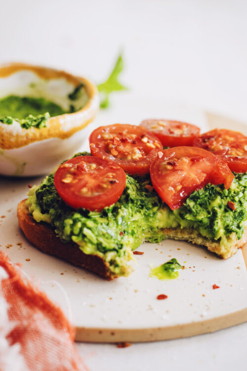 Slice of pesto avocado toast with fresh tomatoes