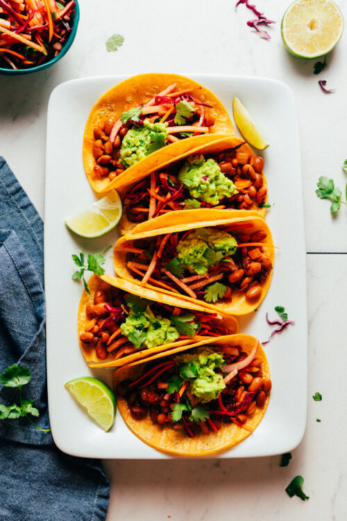 Platter of smoky BBQ bean vegan tacos with jicama slaw and guacamole