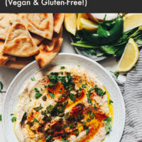 Plate of vegan and gluten-free charred serrano white bean dip with pita bread and serrano peppers around it