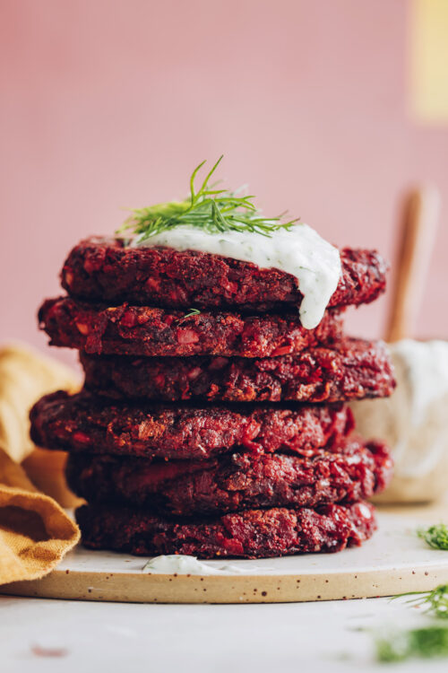 Stack of beet fritters topped with vegan yogurt sauce