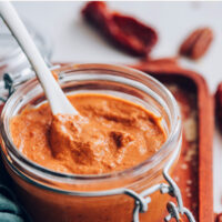 Jar of creamy vegan and gluten-free chipotle pecan pesto with a spoon in it