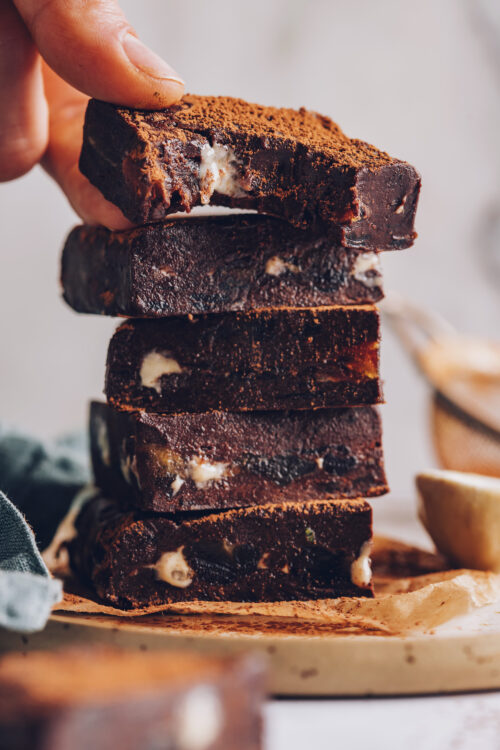 Picking up a Honey Mama-inspired tahini date chocolate bar from a stack