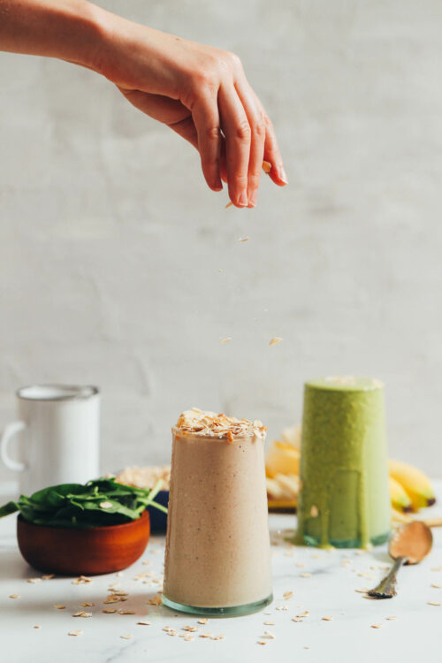 Sprinkling rolled oats on a peanut butter banana smoothie