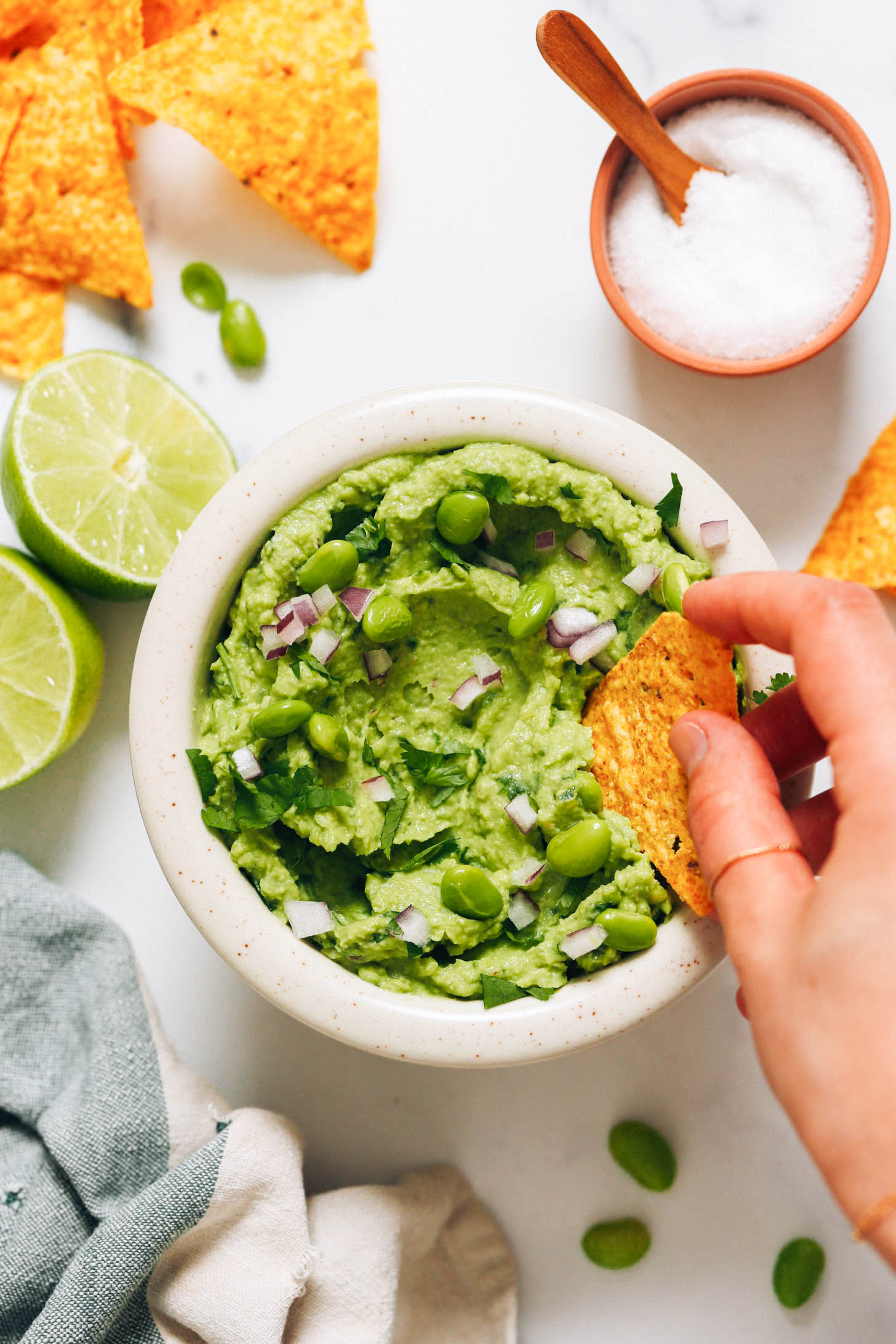 Dipping a tortilla chip into a bowl of edamame guacamole