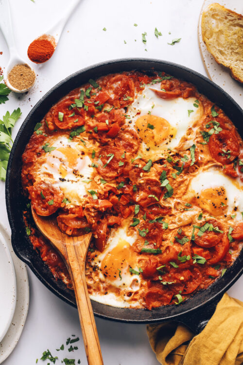 Wooden spoon in a skillet of shakshuka