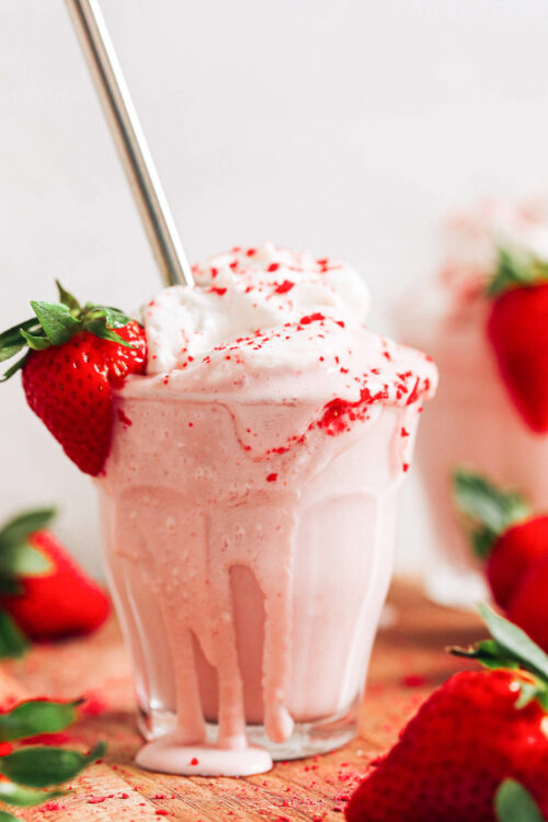 Metal straw in an overflowing glass with our strawberry milkshake recipe