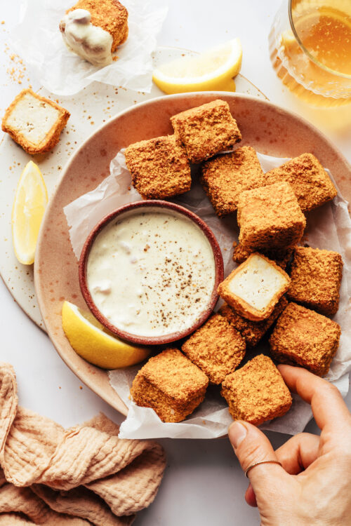 Picking up a tofu nugget from a plate