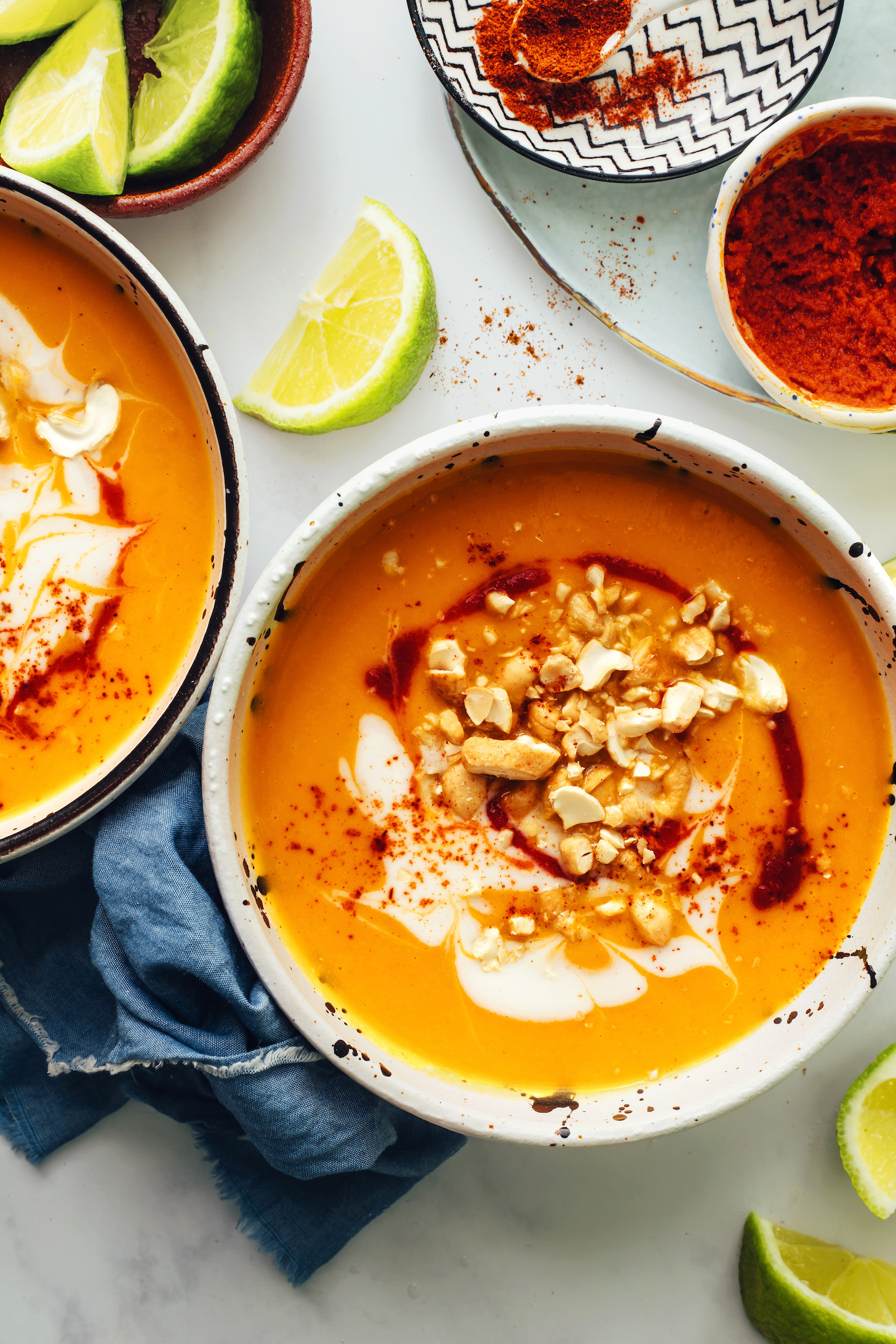 Curry paste, cayenne, and lime wedges next to two bowls of spicy butternut squash soup made in the Instant Pot