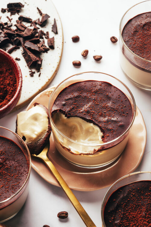 Spoonful of vegan tiramisu pudding next to a dessert cup
