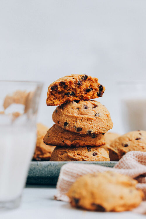 Stack of pumpkin chocolate chip cookies with the top one in the stack partially eaten