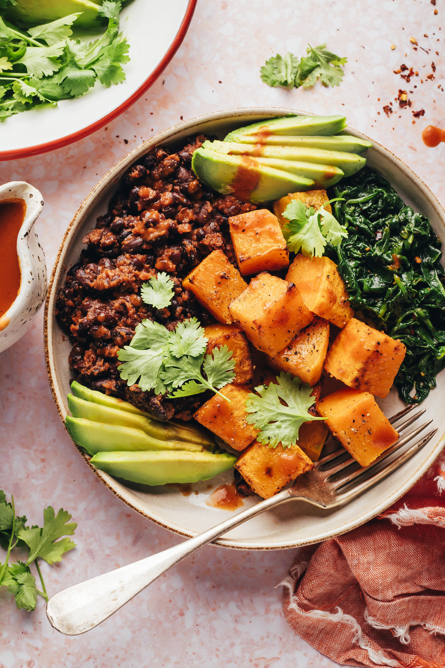 Breakfast bowl with roasted squash, avocado, sautéed spinach, seasoned black beans, and cilantro