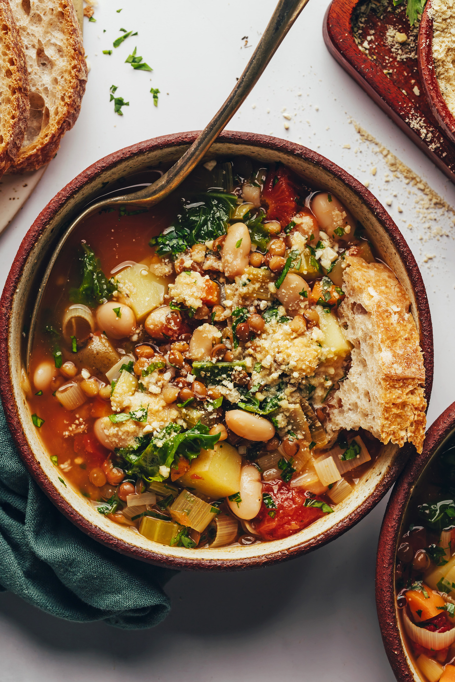 Slices of bread next to and in a bowl of vegetable soup with beans and lentils