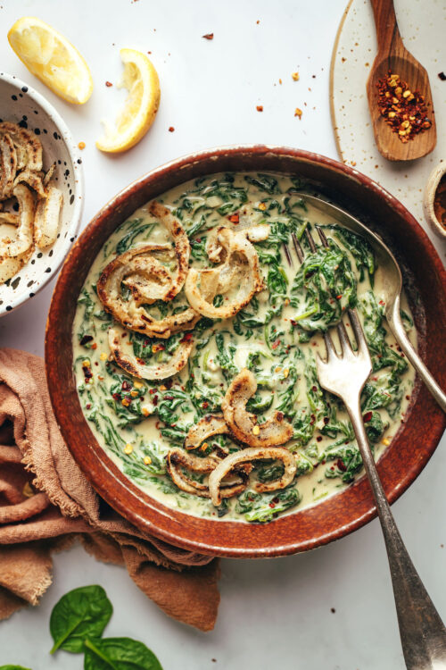 Bowl of vegan creamed spinach topped with crispy fried onions